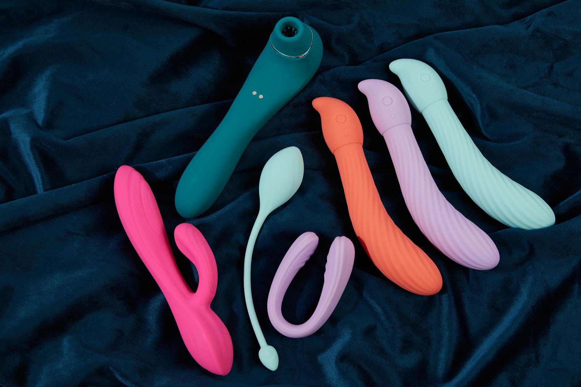 Vibrant collection of clitoral vibrators on dark blue fabric