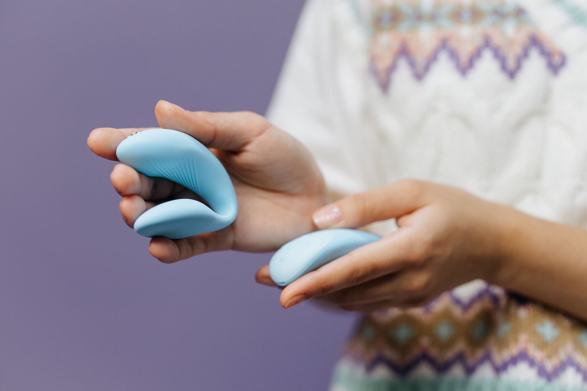 Close-up of hands holding a sleek vibrator, representing intimate pleasure during hormonal transitions