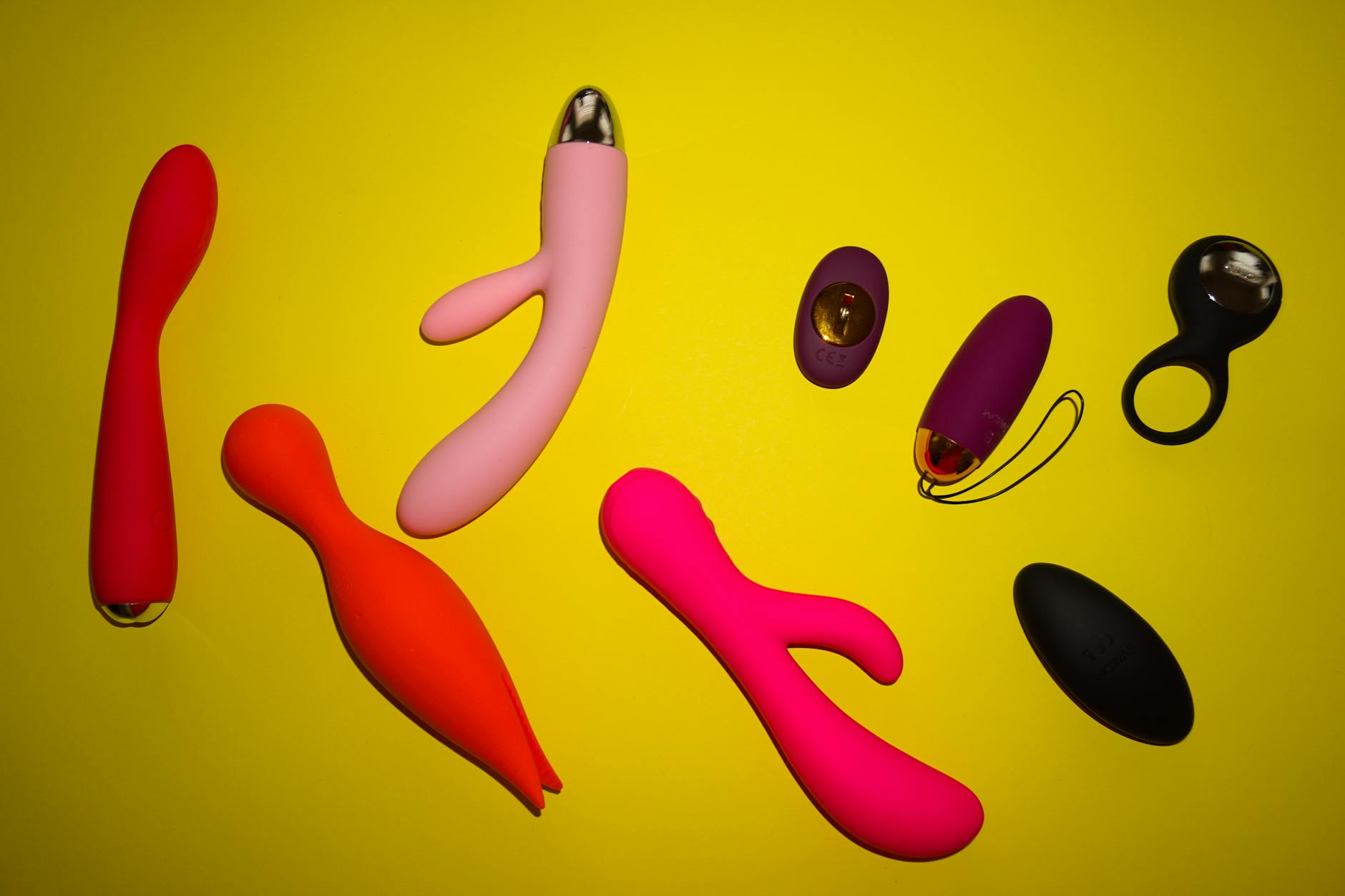 Colorful vibrators arranged on a bright yellow surface, showcasing modern designs for intimacy