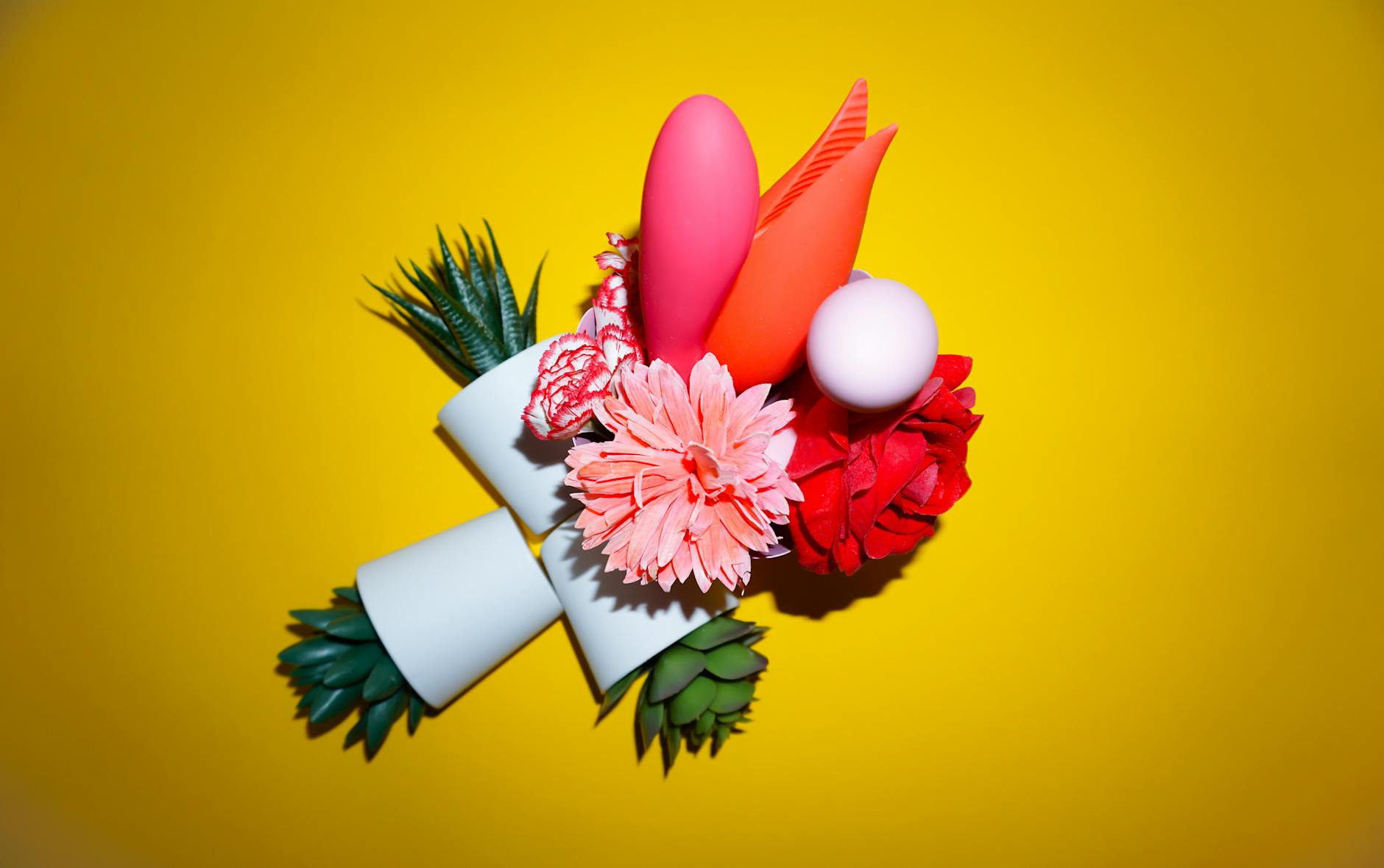 A yellow silicone vibrator surrounded by peeled bananas on a bright yellow background