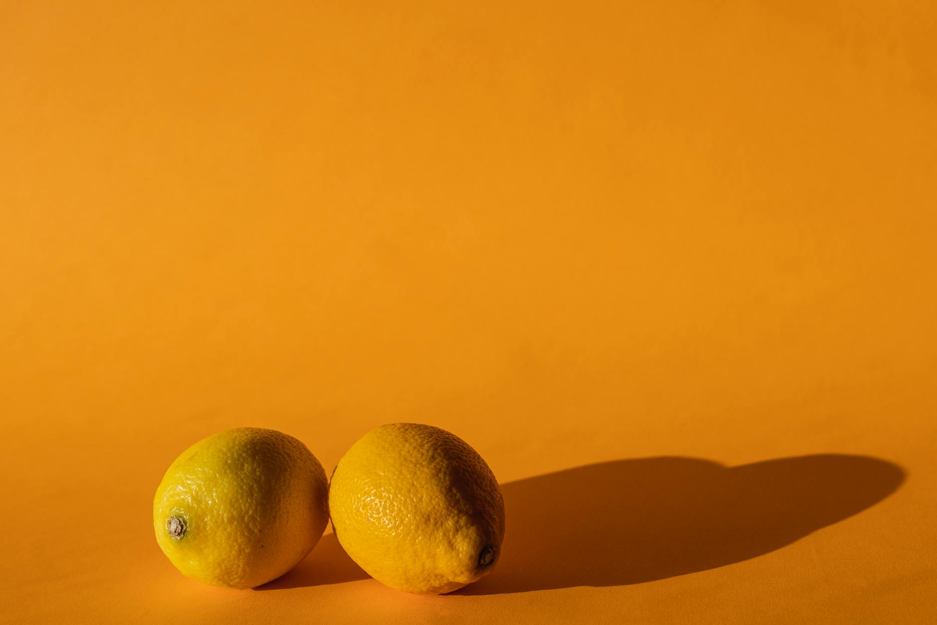 Citrons jaunes vifs disposés sur un fond jaune moderne en lumière naturelle