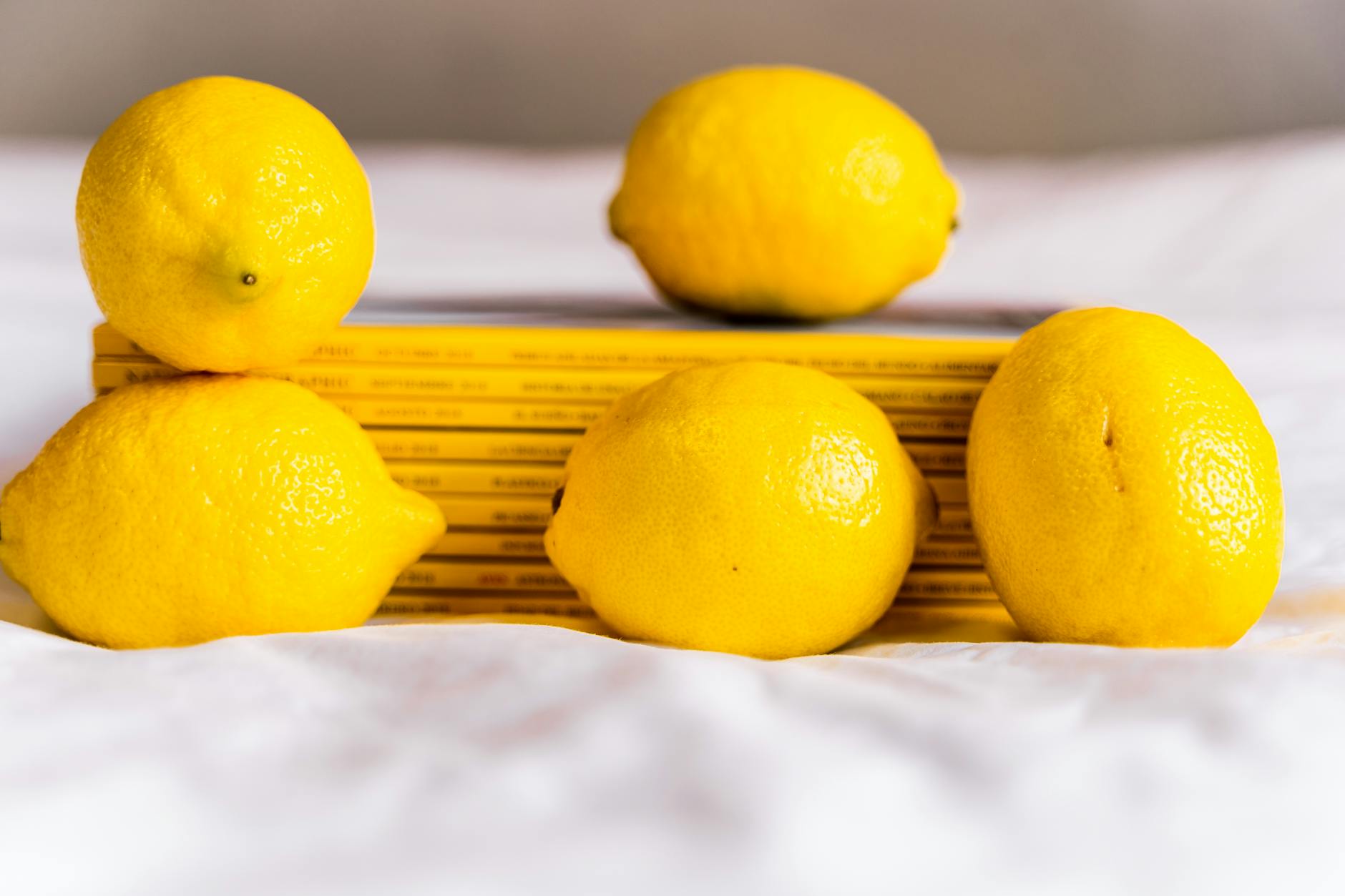Hand holding a fresh lemon against a bright yellow background, symbolizing clarity and sensuality